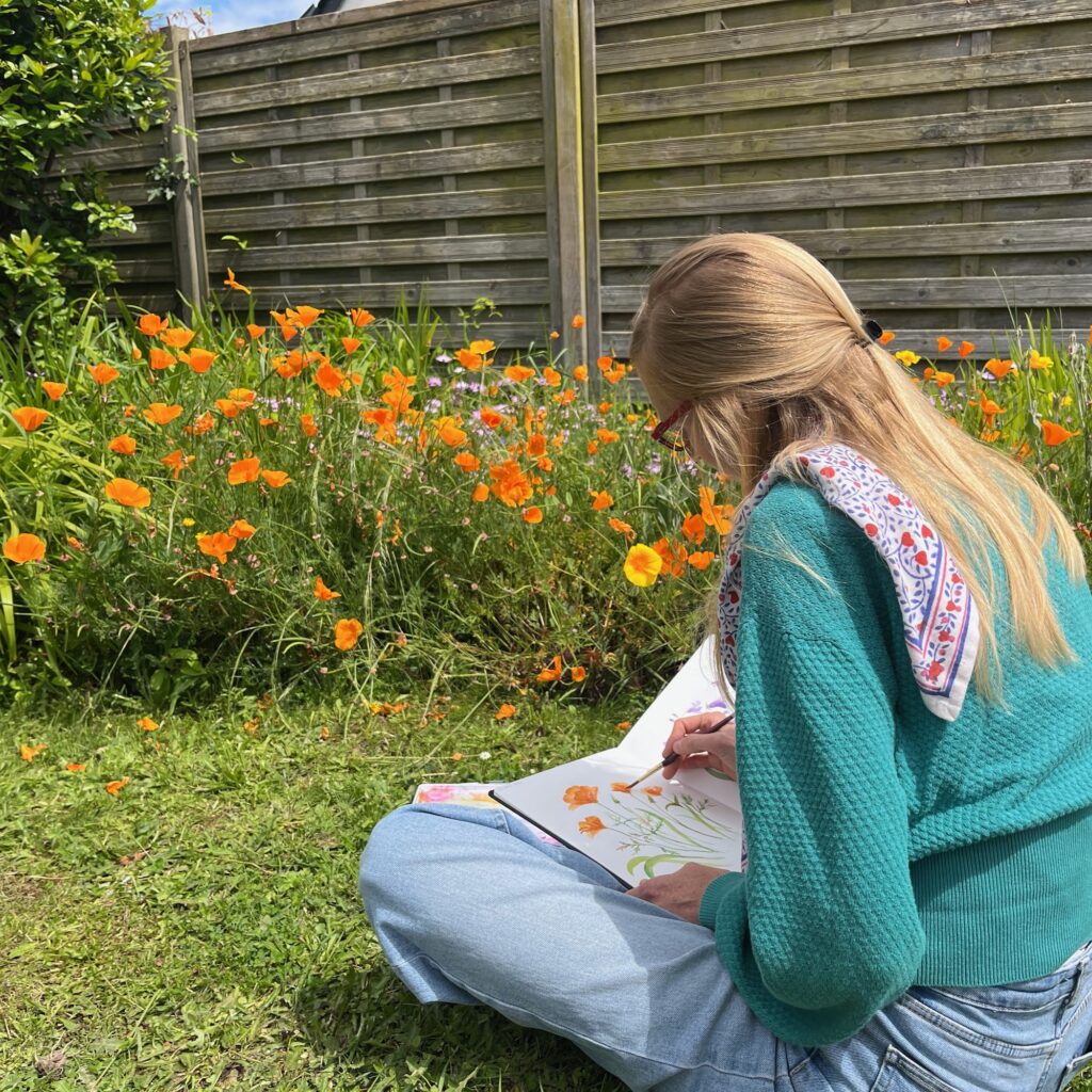 Nadège Vicaire assise, dessine dans un jardin